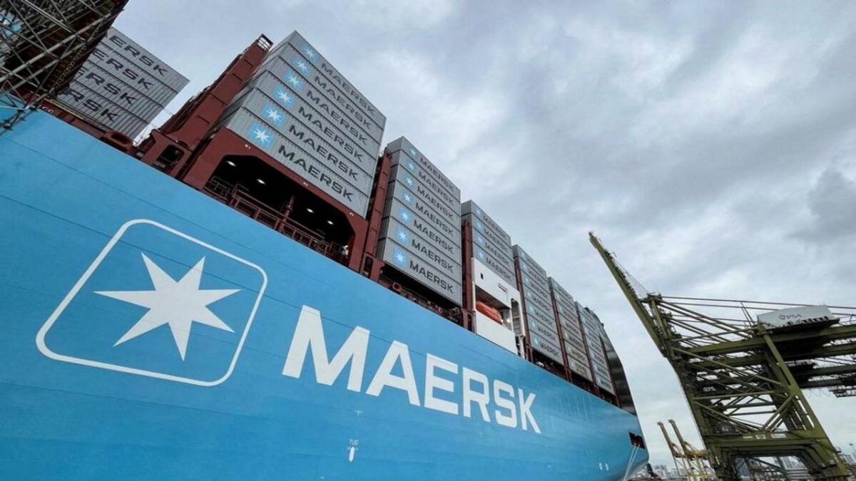 A large Maersk container ship navigates the sea, packed with shipping containers.