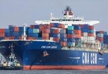 A large container ship in a port, representing CMA CGM's fleet and the Le Havre biomethane project.