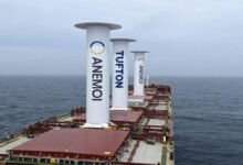 Bulk carrier ship with prominent rigid wind sails for propulsion at sea.
