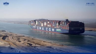 A massive container ship transits the Suez Canal under a clear sky.