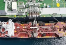 An LNG bunker vessel refuels a large cargo ship at sea.