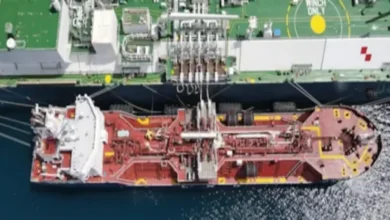An LNG bunker vessel refuels a large cargo ship at sea.